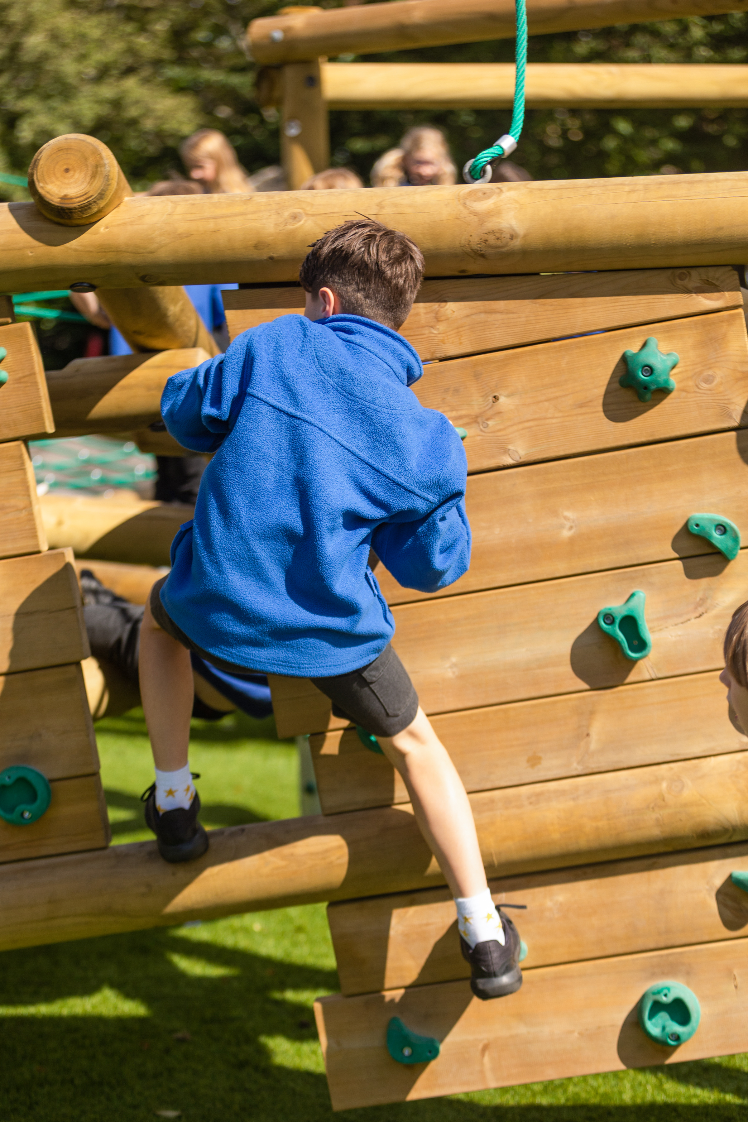 Child climbing wooden outdoor climbing wall